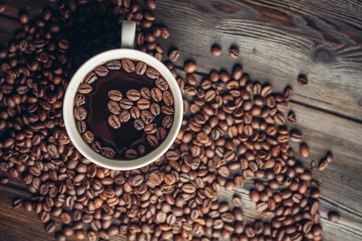 cup with aromatic drink and coffee beans on wooden background top view. High quality photo