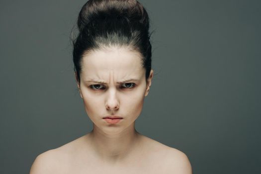 pretty woman with bare shoulders displeased look clear skin gray background. High quality photo