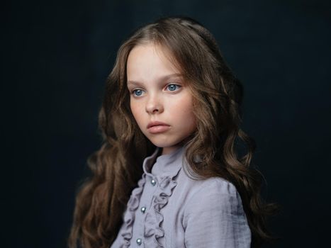portrait of a beautiful girl in a gray dress on a dark background and curly hair blue eyes. High quality photo
