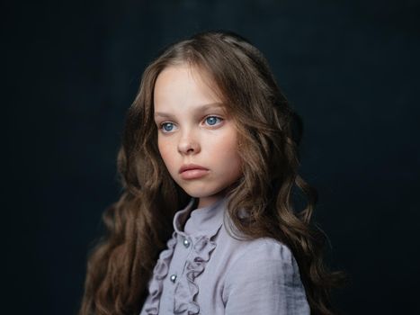 portrait of a beautiful girl in a gray dress on a dark background and curly hair blue eyes. High quality photo