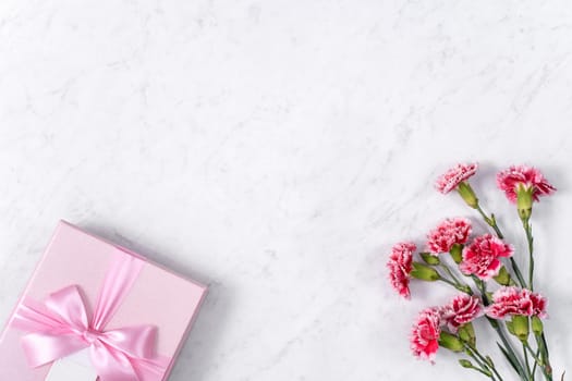 Concept of Mother's day holiday greeting gift design with carnation bouquet on white marble background