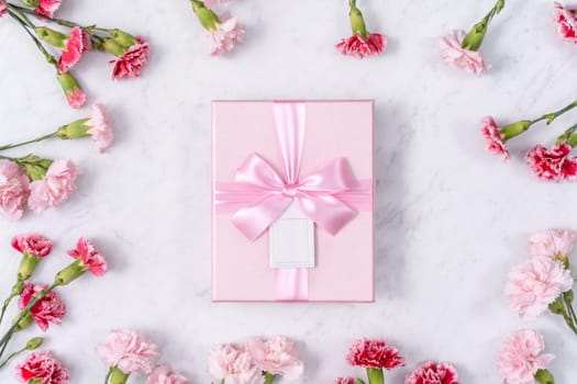 Concept of Mother's day holiday greeting gift design with carnation bouquet on white marble background