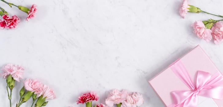 Concept of Mother's day holiday greeting gift design with carnation bouquet on white marble background