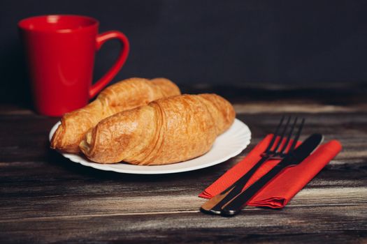 fresh croissant on a plate kitchen utensils coffee cup breakfast. High quality photo