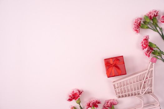 Concept of Mother's day holiday greeting design with carnation bouquet and gift on pink background