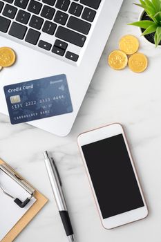 Top view of financial plan concept with credit card, laptop, note on white office table background.