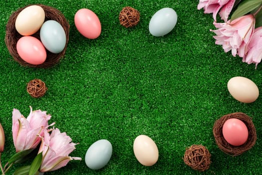 Colorful Easter eggs in the nest with pink lily flower on a lawn grass background.