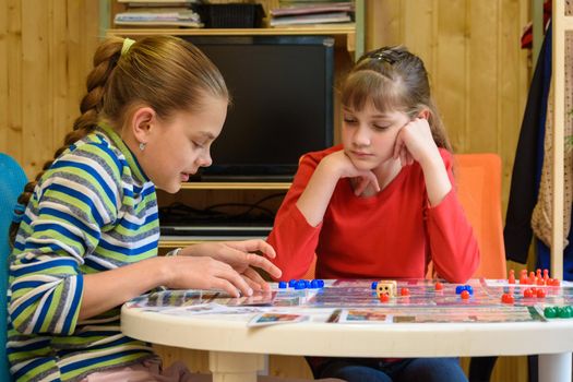 A girl explains to another girl how to play a board game