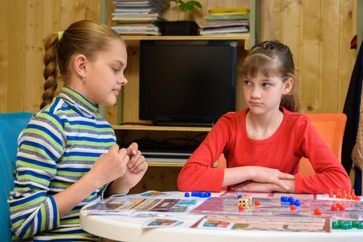 A girl is waiting for another girl to make another move while playing board games