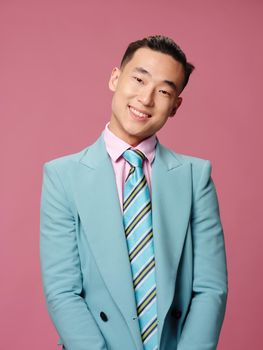 Cheerful man of Asian appearance blue suit self confidence pink background. High quality photo