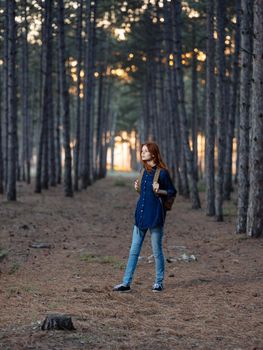 Pretty woman travels in the forest with a backpack on her back and in a blue shirt. High quality photo