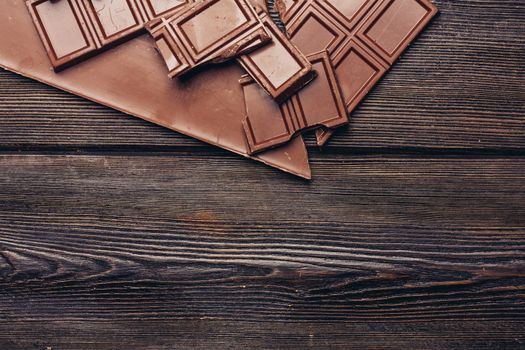 broken chocolate bar diagonal cubes texture wood background. High quality photo