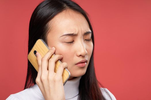 woman asian appearance talking on the phone lifestyle technology red background. High quality photo