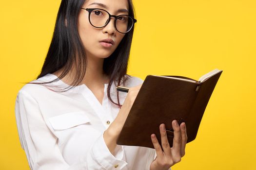 woman of asian appearance wearing glasses elegant style notepad in student hands. High quality photo