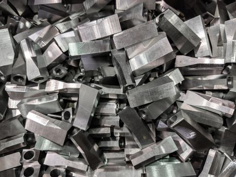 full frame industrial background of pile of shiny steel flat grinded parts - close-up with selective focus