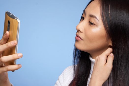 woman asian appearance phone in hand communicating internet blue background. High quality photo