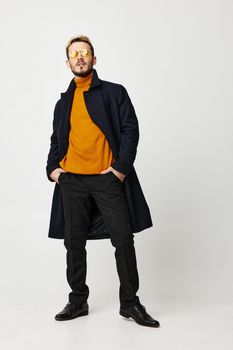 confident man in coat orange sweater pants shoes model glasses. High quality photo