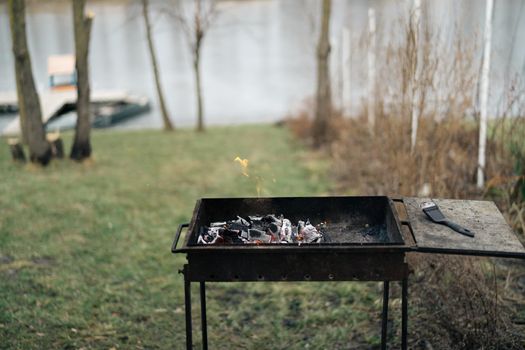 brazier outdoor cooking small river fire boat in the background and trees. High quality photo