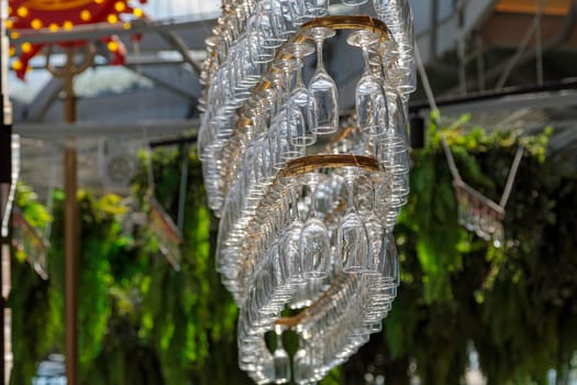 Several rows of champagne glasses hang on a chandelier-shaped counter. Decorative modern chandelier.