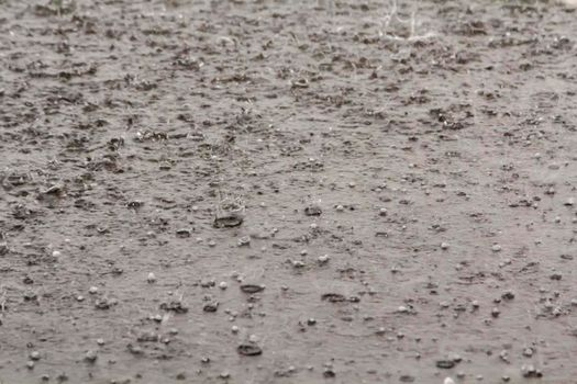 Heavy rain with hail is falling along the highway. Large drops with lumps of snow
