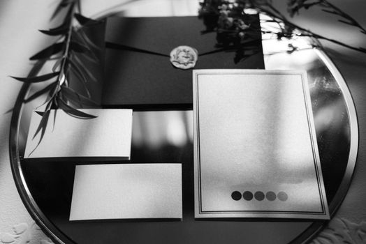 wedding invitation in a gray envelope on a table with green sprigs