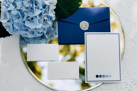 wedding invitation in a gray envelope on a table with green sprigs