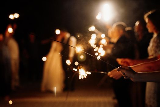 sparklers at the wedding, a couple of newlyweds on the background