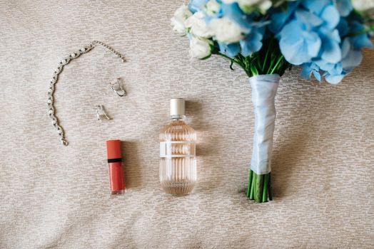elegant bottle of perfume on the armchair with a pink necklace of the bride