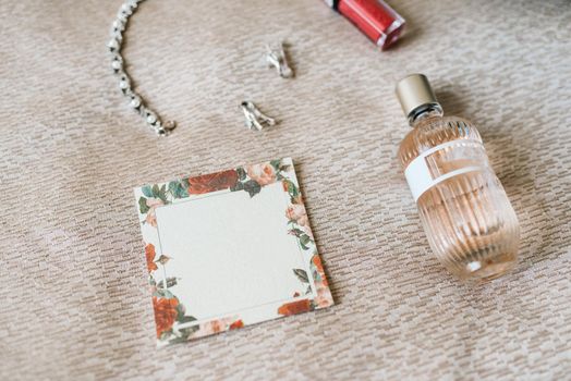 elegant bottle of perfume on the armchair with a pink necklace of the bride