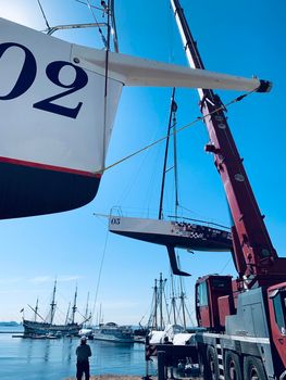 Russia, St.Petersburg, 26 May 2020: Port Hercules, the big industrial crane lifts the sailboat and floats it, the beginning of a season of sailing, a skyscraper on a background, sailboat is groundless, sunny weather