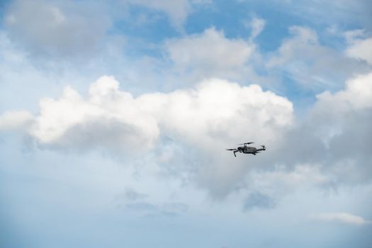 The flying soaring drone in the sky, the blue sky with white clouds, sunny weather, Turning propellers, nobody. High quality photo