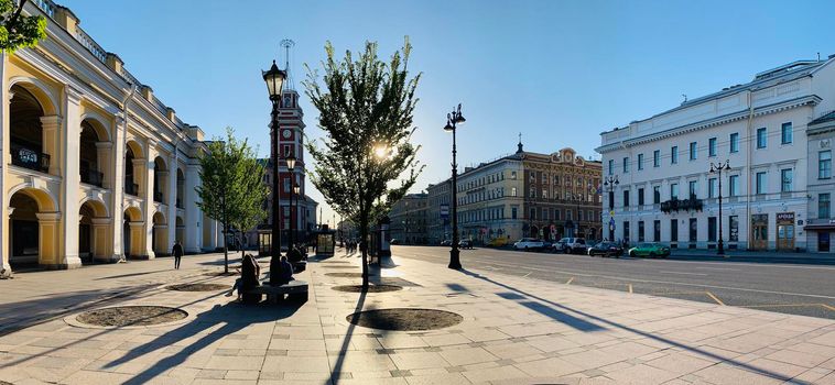Russia, St.Petersburg, 02 June 2020: The architecture of Nevsky Prospect at sunset during pandemic of virus Covid-19, Square in front of Gostiny yard, long shadows of people and cars. Panoramic image
