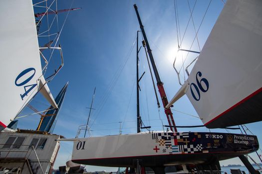 Russia, St.Petersburg, 26 May 2020: Port Hercules, the big industrial crane lifts the sailboat and floats it, the beginning of a season of sailing, a skyscraper on a background, sailboat is groundless, sunny weather