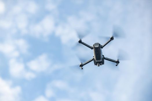 The flying soaring drone in the sky, the blue sky with white clouds, sunny weather, Turning propellers, nobody. High quality photo