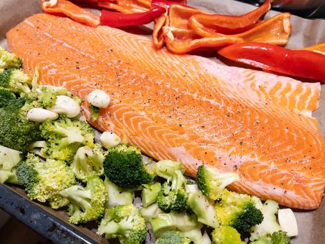 A large piece of red fish fillet lies on the prostena, vegetables ready to be locked, broccoli, red sweet pepper. High quality photo