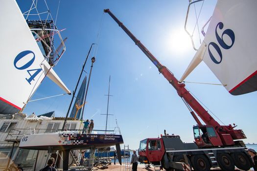 Russia, St.Petersburg, 26 May 2020: Port Hercules, the big industrial crane lifts the sailboat and floats it, the beginning of a season of sailing, a skyscraper on a background, sailboat is groundless, sunny weather