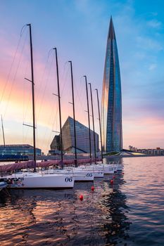 Russia, St.Petersburg, 03 July 2020: The skyscraper Lakhta center at sunset, Reflection of the sunset sky in a glass facade of building, It is the highest skyscraper in Europe, Sailboats in port at a skyscraper