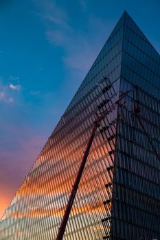 Russia, St.Petersburg, 03 July 2020: The color image of skyscraper Lakhta center at sunset, Reflection of the sunset sky in a glass facade of the building, It is the highest skyscraper in Europe, Completion of construction, Huge construction crane