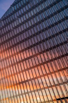 Reflection of the sunset sky in a glass facade of the building, skyscraper at sunset