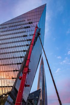 Russia, St.Petersburg, 03 July 2020: The color image of skyscraper Lakhta center at sunset, Reflection of the sunset sky in a glass facade of the building, It is the highest skyscraper in Europe, Completion of construction, Huge construction crane