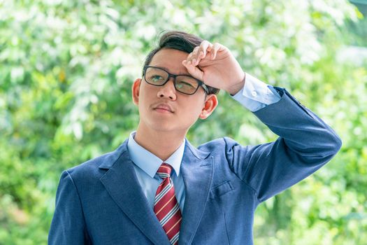 Young asian business men portrait in suit and wear eyeglasses standing outside in a park during sunny day