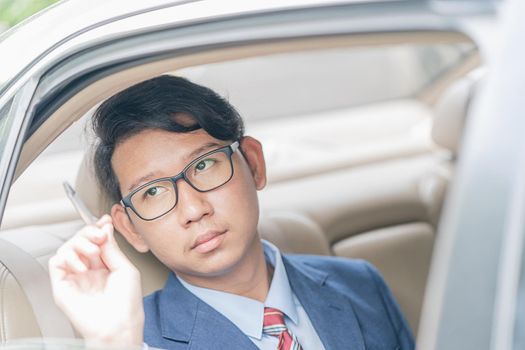 Young asian business men portrait in suit working in the backseat of a car