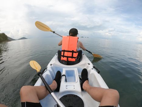 Couple traveler kayaking together on the sea from backward view.