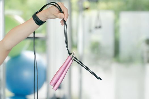 Woman hand holding pink jumping rope in gym. fitness and sport concept.