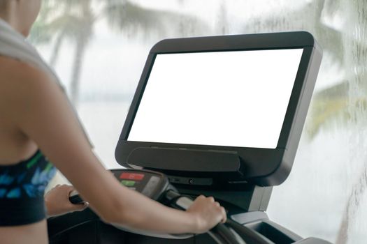 Woman is working out in gym. Doing cardio training on treadmill with white screen mockup , large windows with ocean view raining outside.