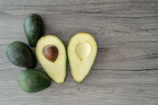 Cut half, sliced fresh green avocado on brown wooden table. Fruits healthy food concept.