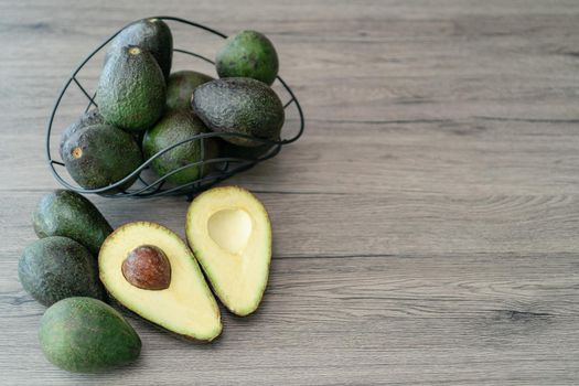 Cut half, sliced fresh green avocado on brown wooden table. Fruits healthy food concept.