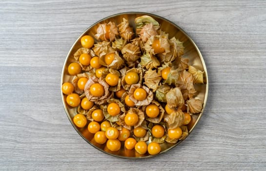 Top view pile of cape gooseberry fruit in the gold plate.