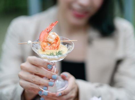 Grilled shrimp with cocktail sauce in woman hand.