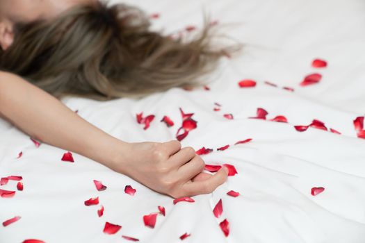 Women hand pulling or grasping white sheets. Hand sign orgasm of woman on white bed sheet with rose petals.